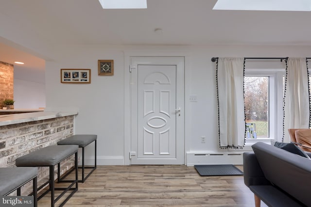 entrance foyer featuring a skylight, light hardwood / wood-style flooring, and a baseboard radiator