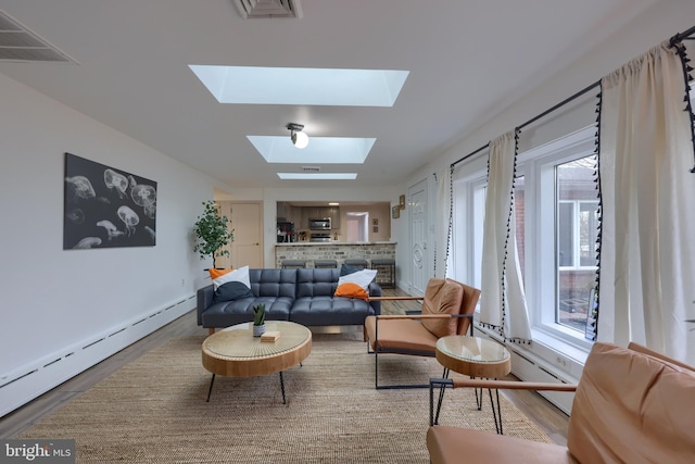 living room featuring a skylight, hardwood / wood-style floors, and a baseboard radiator