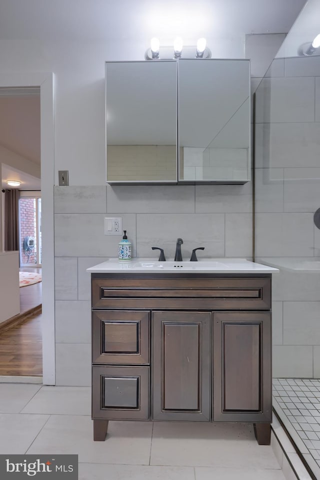 bathroom with tile patterned floors, vanity, a shower, and tile walls