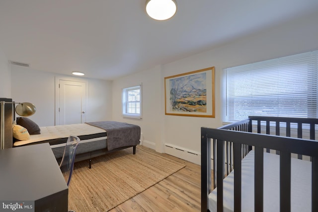 bedroom with hardwood / wood-style flooring and baseboard heating