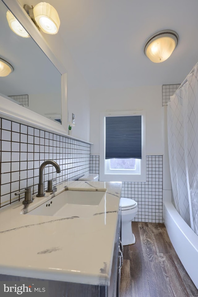 full bathroom with shower / bath combo, vanity, hardwood / wood-style flooring, tile walls, and toilet