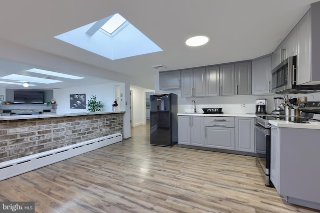 kitchen with gray cabinets, light hardwood / wood-style floors, stainless steel appliances, and a baseboard radiator