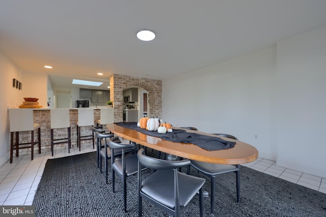 dining area featuring a skylight and light tile patterned flooring