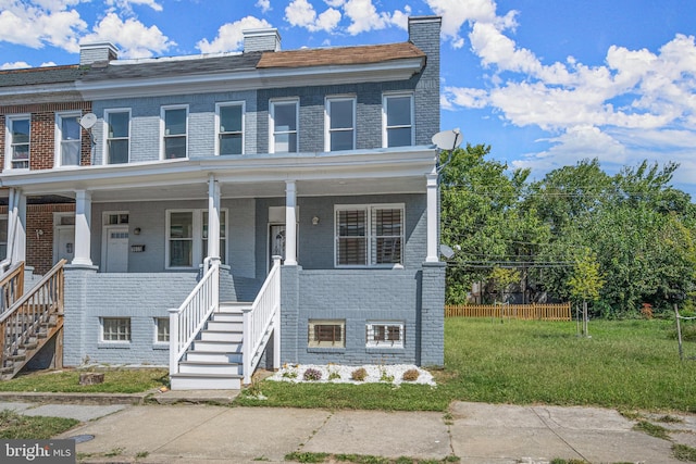 townhome / multi-family property with covered porch and a front yard