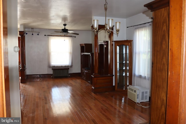 foyer entrance featuring a healthy amount of sunlight, ceiling fan with notable chandelier, radiator heating unit, and dark wood-type flooring