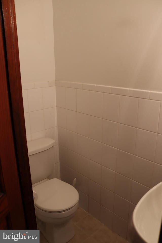 bathroom with tile walls, toilet, and tile patterned floors