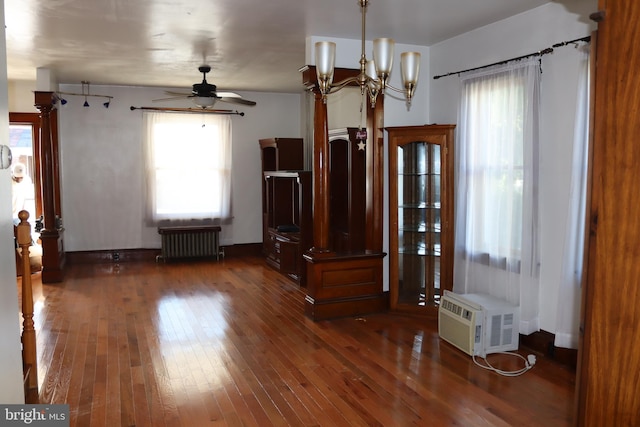 interior space featuring dark hardwood / wood-style flooring, ceiling fan with notable chandelier, plenty of natural light, and radiator heating unit