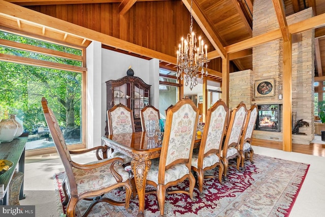 dining room with a chandelier, beamed ceiling, high vaulted ceiling, hardwood / wood-style floors, and a stone fireplace