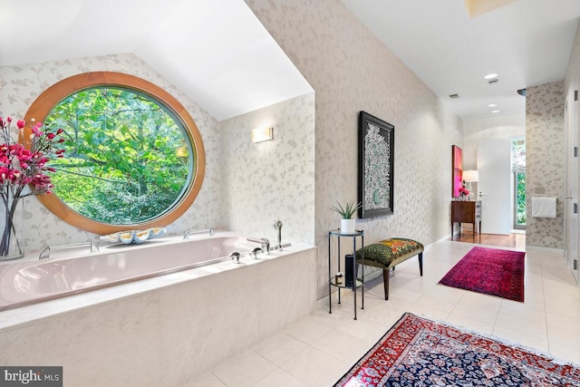 bathroom featuring tiled tub, lofted ceiling, and tile patterned floors