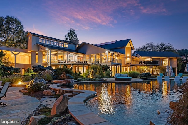 back house at dusk featuring a balcony