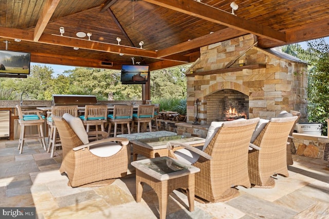 view of patio with an outdoor bar, area for grilling, an outdoor stone fireplace, and a gazebo