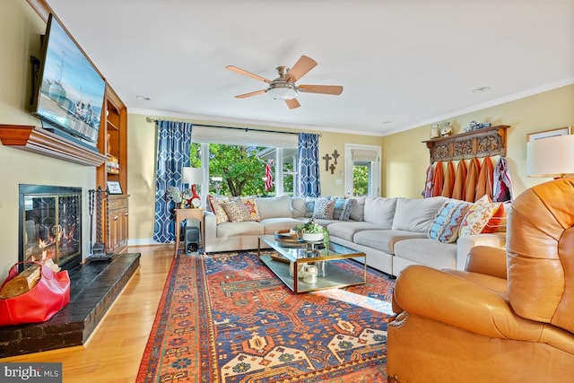 living room with light wood-type flooring, ornamental molding, and ceiling fan