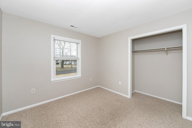 unfurnished bedroom featuring carpet floors, baseboards, visible vents, and a closet