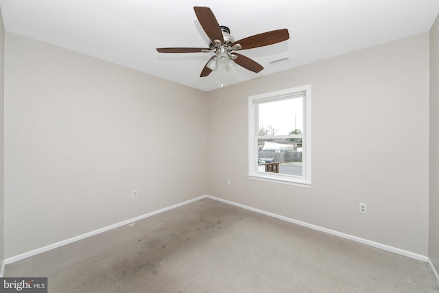 carpeted empty room featuring baseboards, visible vents, and a ceiling fan