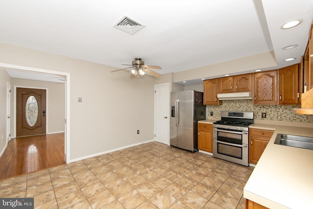 kitchen featuring under cabinet range hood, stainless steel appliances, a sink, visible vents, and light countertops