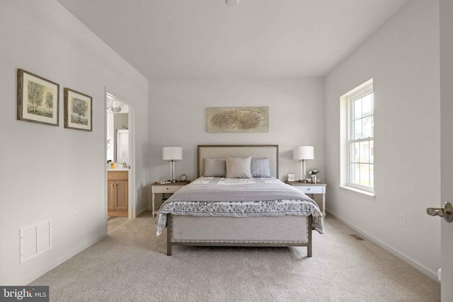 bedroom with light colored carpet, visible vents, ensuite bath, and baseboards