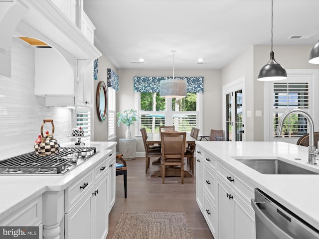 kitchen featuring white cabinets, sink, wood-type flooring, decorative light fixtures, and stainless steel appliances