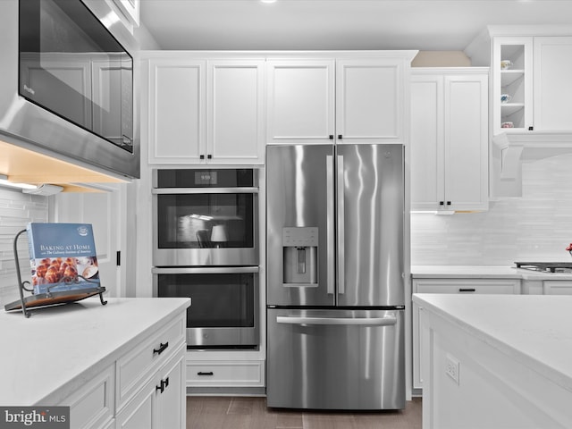 kitchen with stainless steel appliances, white cabinetry, dark hardwood / wood-style floors, and backsplash