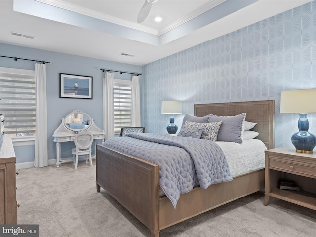 carpeted bedroom featuring a raised ceiling, ornamental molding, and ceiling fan