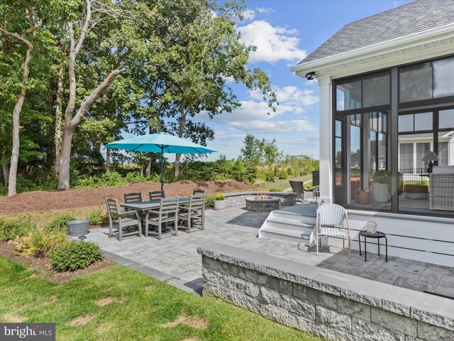 view of patio / terrace with a sunroom and an outdoor fire pit