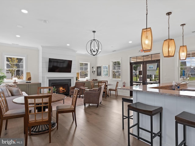 dining room featuring ornamental molding, wood-type flooring, a chandelier, and a wealth of natural light