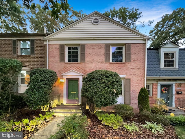 view of front of house featuring roof with shingles and brick siding