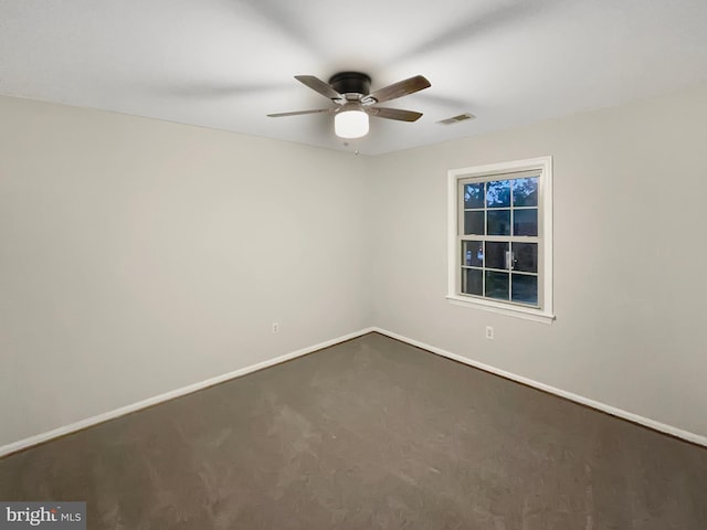 spare room featuring baseboards, a ceiling fan, visible vents, and dark colored carpet
