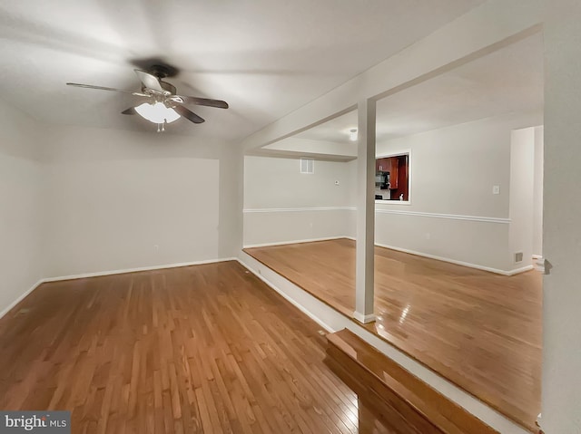 interior space with baseboards, a ceiling fan, and wood finished floors