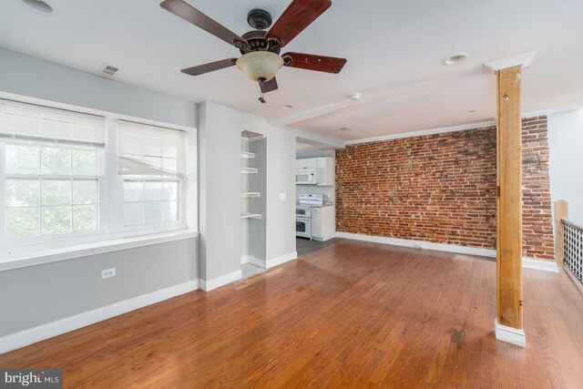 unfurnished living room with wood-type flooring, ceiling fan, and brick wall