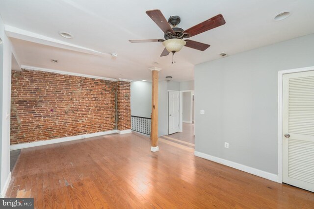 interior space featuring brick wall, light hardwood / wood-style flooring, and ceiling fan