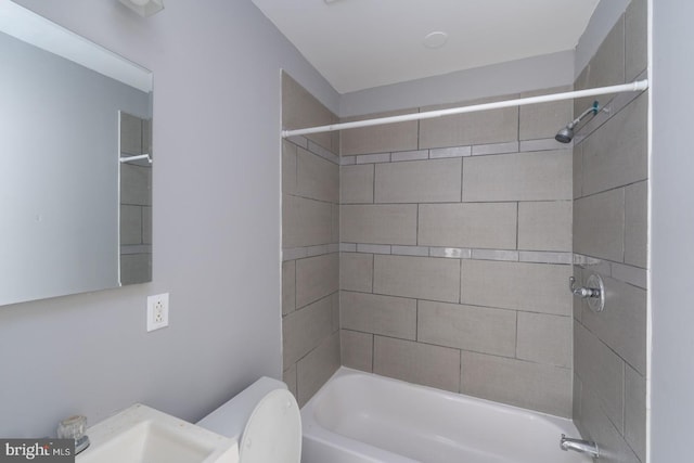 full bathroom featuring sink, tiled shower / bath, and toilet