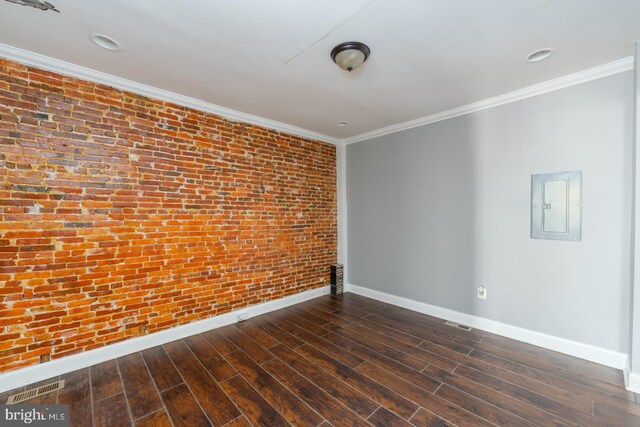 spare room with brick wall, ornamental molding, electric panel, and dark wood-type flooring