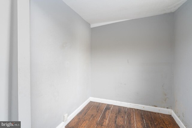 spare room featuring lofted ceiling and dark wood-type flooring