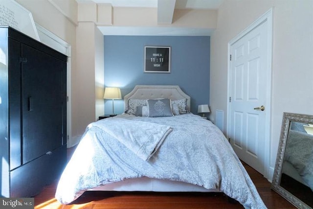 bedroom with dark hardwood / wood-style floors and beam ceiling