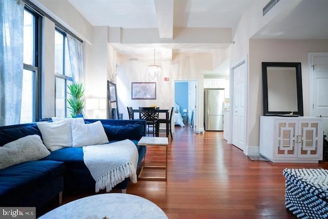 living room featuring beamed ceiling, hardwood / wood-style flooring, and a chandelier