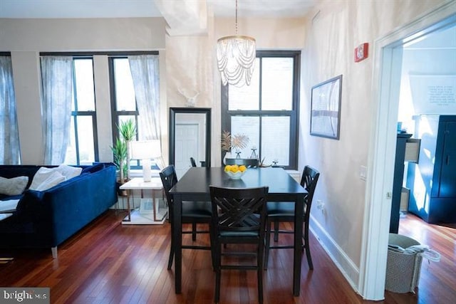 dining room with a wealth of natural light, an inviting chandelier, and dark hardwood / wood-style flooring