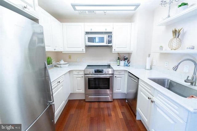 kitchen featuring dark wood-type flooring, stainless steel appliances, white cabinetry, and sink