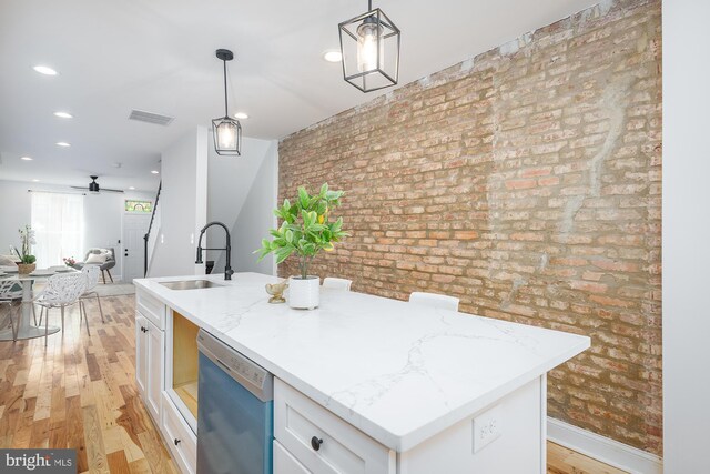 kitchen with white cabinetry, an island with sink, sink, appliances with stainless steel finishes, and wall chimney range hood