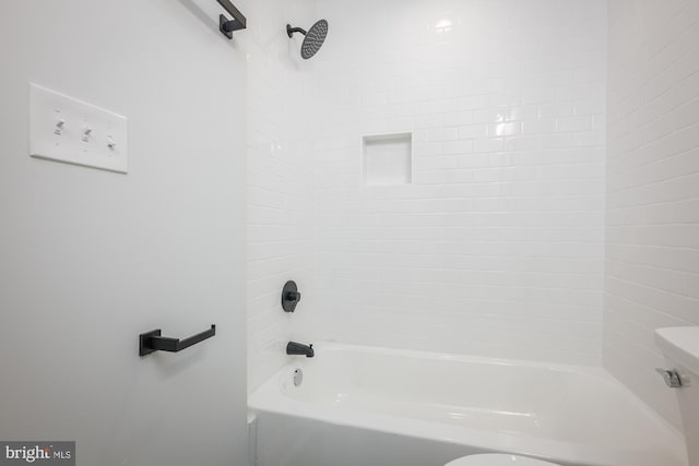 bathroom featuring tiled shower / bath and toilet