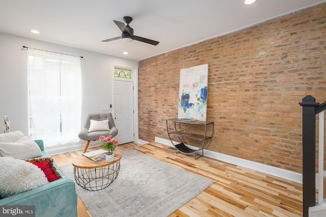 living room featuring brick wall, ceiling fan, a healthy amount of sunlight, and wood-type flooring