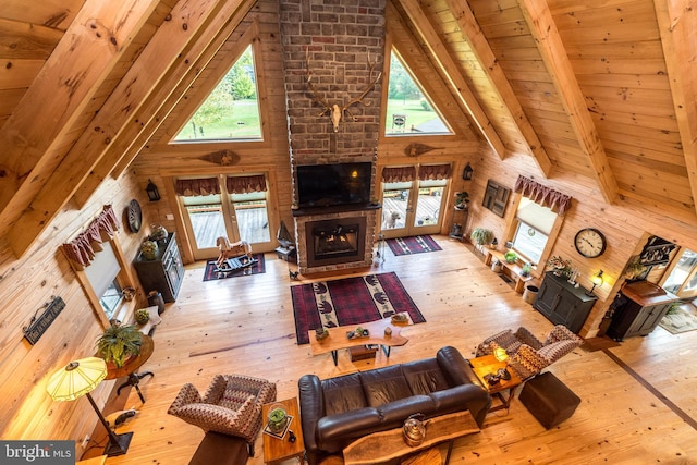 living room with a brick fireplace, light hardwood / wood-style flooring, beam ceiling, and high vaulted ceiling