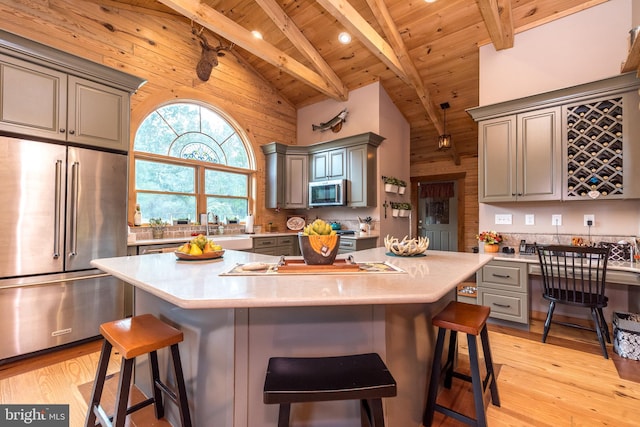 kitchen featuring a kitchen breakfast bar, stainless steel appliances, beam ceiling, and high vaulted ceiling