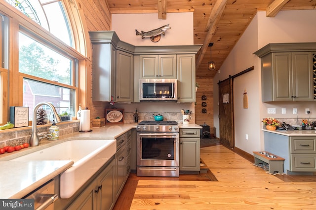 kitchen with a barn door, beam ceiling, stainless steel appliances, and wooden ceiling