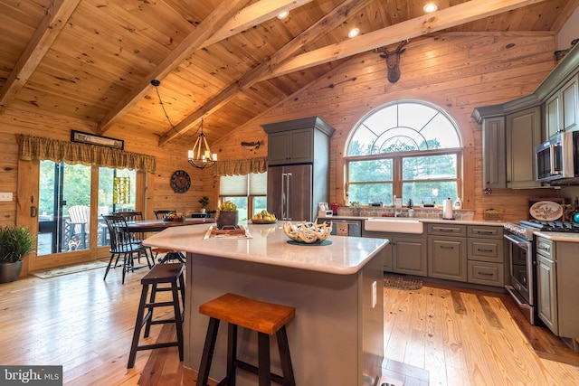 kitchen featuring appliances with stainless steel finishes, wood walls, plenty of natural light, and a center island