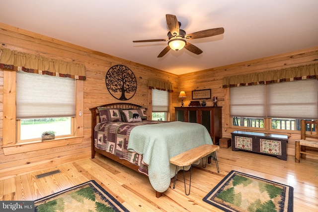 bedroom with ceiling fan, wooden walls, and hardwood / wood-style floors