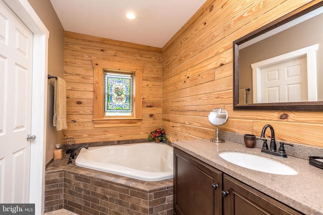 bathroom featuring a relaxing tiled tub, vanity, and wood walls