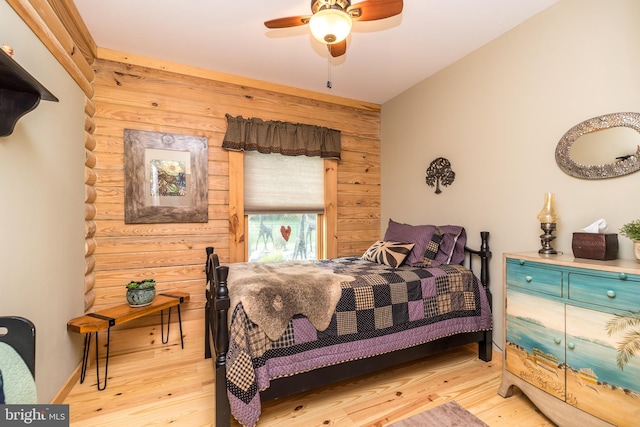 bedroom with light wood-type flooring, ceiling fan, and wooden walls