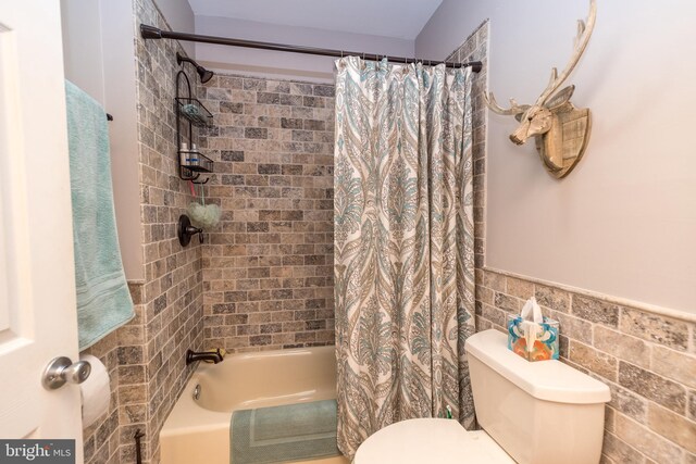 bathroom with shower / bath combination with curtain and toilet