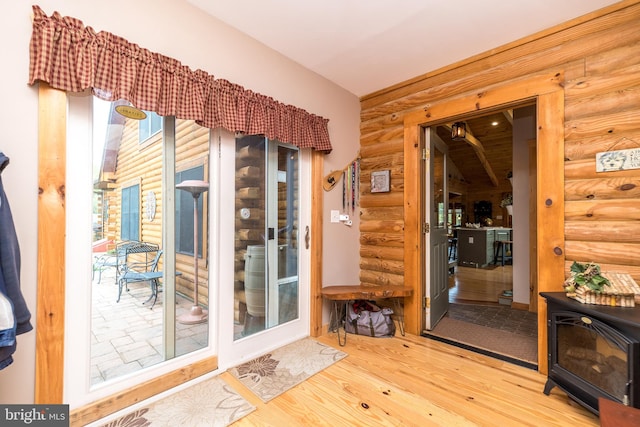 interior space featuring a wood stove, rustic walls, and hardwood / wood-style flooring