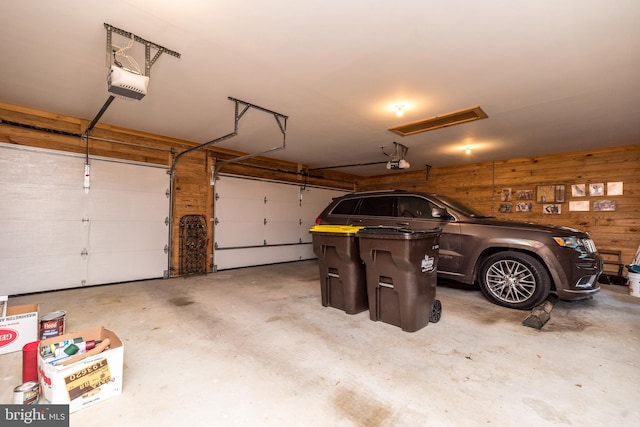 garage featuring a garage door opener and wooden walls